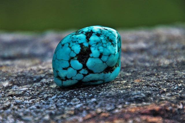Close up image of a small, smooth turquoise stone with light blue and black lines