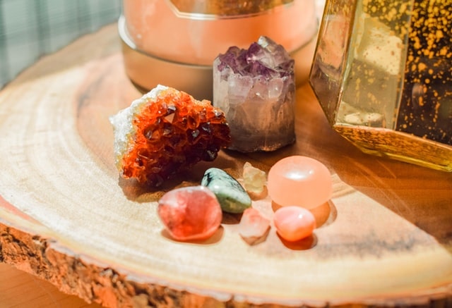 Various colorful crystals displayed on a nightstand made from a tree trunk slice