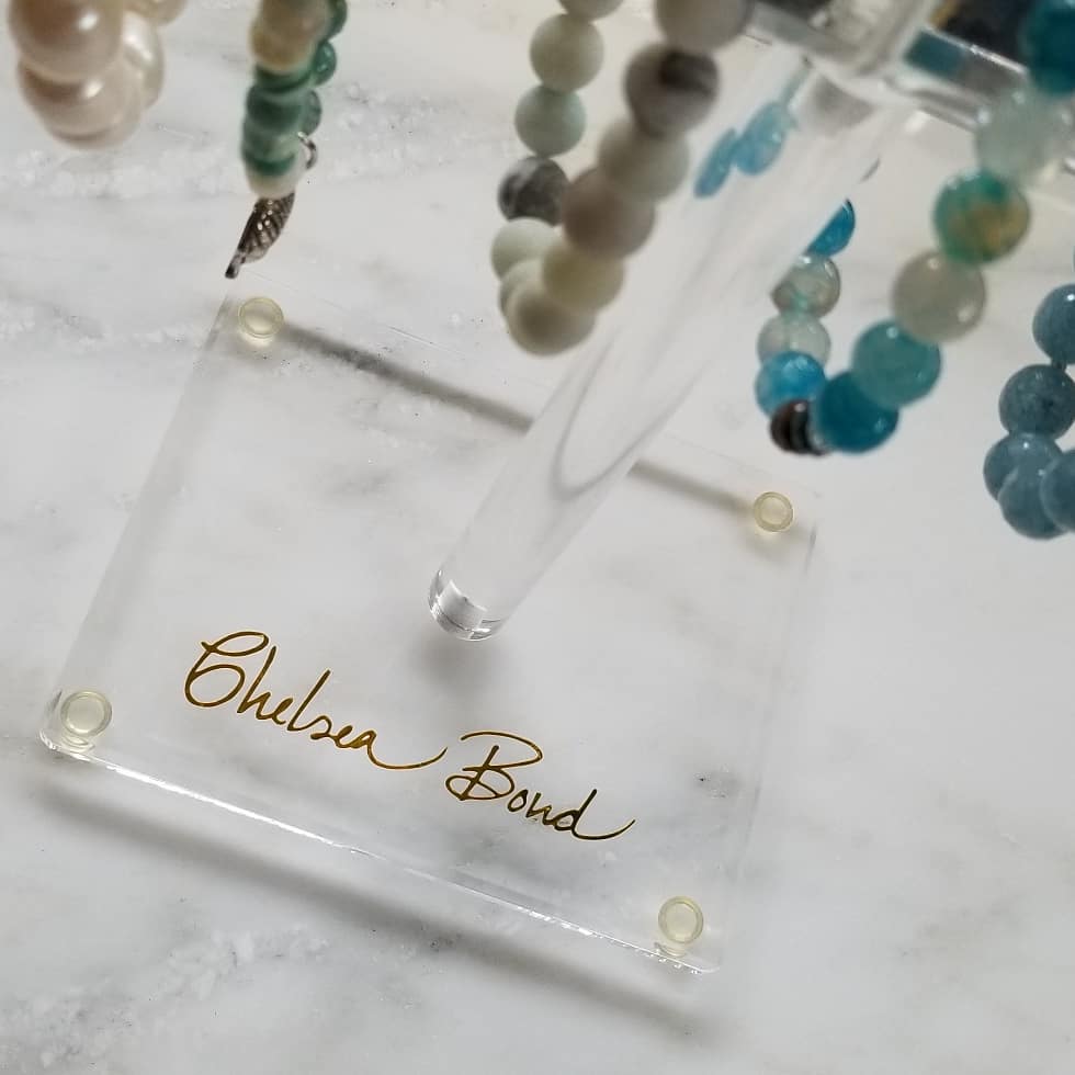 Birds eye view image of turquoise, healing gemstone bracelets hanging on a clear acrylic bracelet display stand