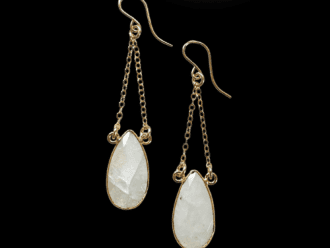 white gemstone earrings hanging from gold chains.