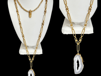 Long gold necklace with druzy pendant displayed on a white bust.