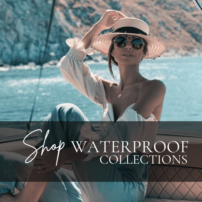 Woman sitting on a boat wearing sunglasses and a hat, showcasing jewelry. Text overlay: "Shop Waterproof Collections."