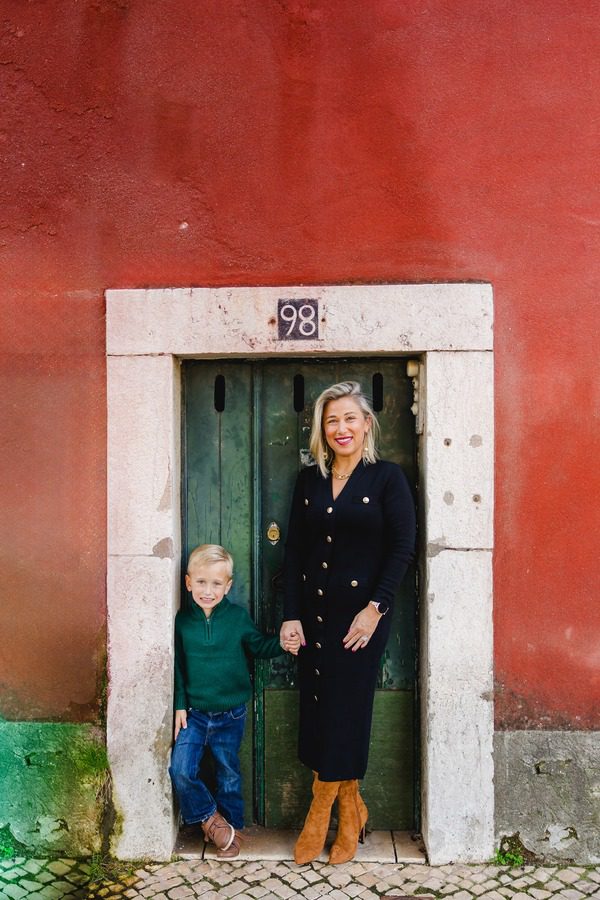 Standing in a doorway in Lisbon against a red wall and green door.