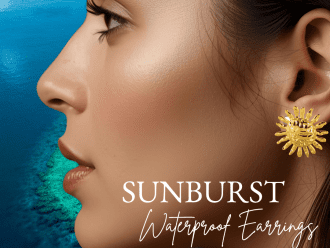 Close-up of a woman wearing Sunburst Waterproof gold post earrings from Chelsea Bond Jewelry, with an ocean-inspired blue background highlighting the radiant sun design.