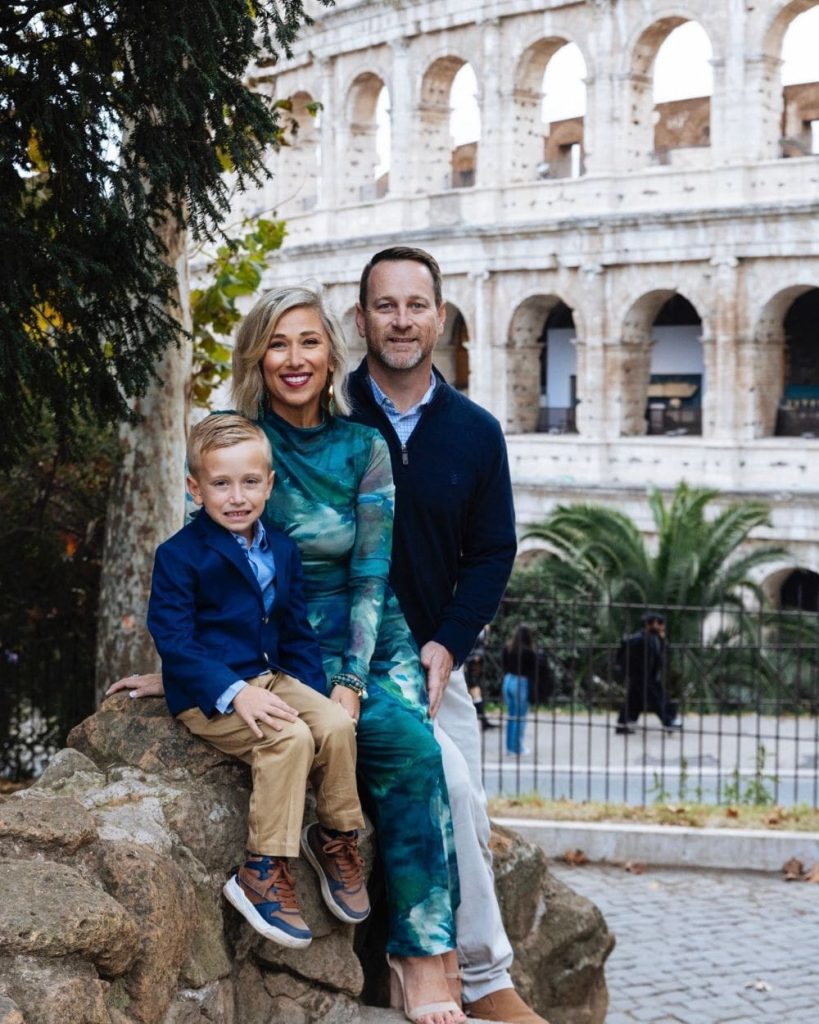 Family sitting under a tree in front of the Colisseum in Rome, Italy.