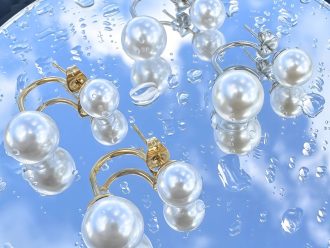 Pearl earrings laying on a mirror table.