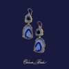 A pair of handmade drop earrings by Chelsea Bond Jewelry featuring two tiers of natural royal blue agate geode slices edged in gold, hanging from 14k gold-filled earwires against a dark blue background.