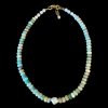 Hand-strung light blue amazonite rondelle necklace with soft white howlite accents, a central irregular white baroque pearl, and a 14k gold-filled clasp with a brass extension chain on a black background.