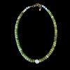 Hand-strung natural green jade rondelle necklace accented with white howlite and dark hematite beads, featuring a central white baroque pearl and a 14k gold-fill clasp with a brass extension chain on a black background.