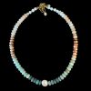 Strung natural gemstone necklace featuring smooth multi-colored rondelle beads transitioning from white to earthy orange and deep teal, centered with a large white freshwater pearl accent and an 18K gold-plated adjustable clasp on a black background.