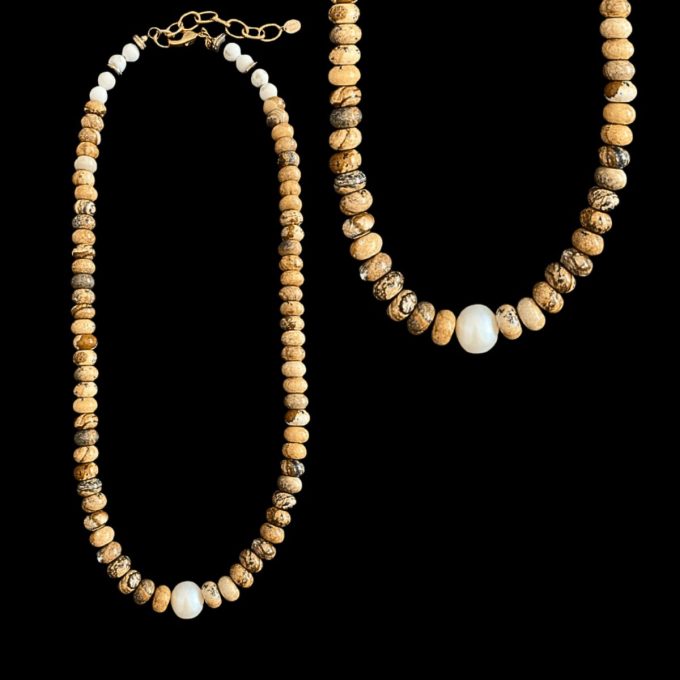 Hand-strung tan picture jasper rondelle necklace displaying natural brown landscape patterns, accented with white howlite beads near a 14k gold-filled clasp and centered with a large round white baroque pearl on a black background.