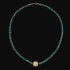 Faceted teal green glass bead strand necklace with a square mother of pearl central connector charm and gold clasp.