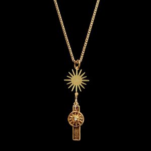 Gold pendant necklace with a sharp multi-ray sunburst charm dropping down to a celestial wheel charm inset with a tiny white crystal, ideal for resort jewelry collections.