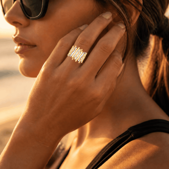 Waterproof two-tone gold and silver wavy statement ring worn on a woman's hand at the beach during sunset.
